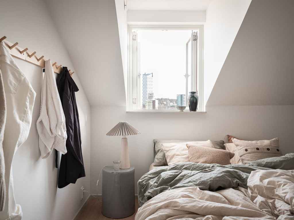 A bedroom with white walls and neutral, warm textiles