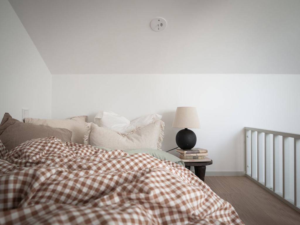 A loft bed with neutral textiles on the bed