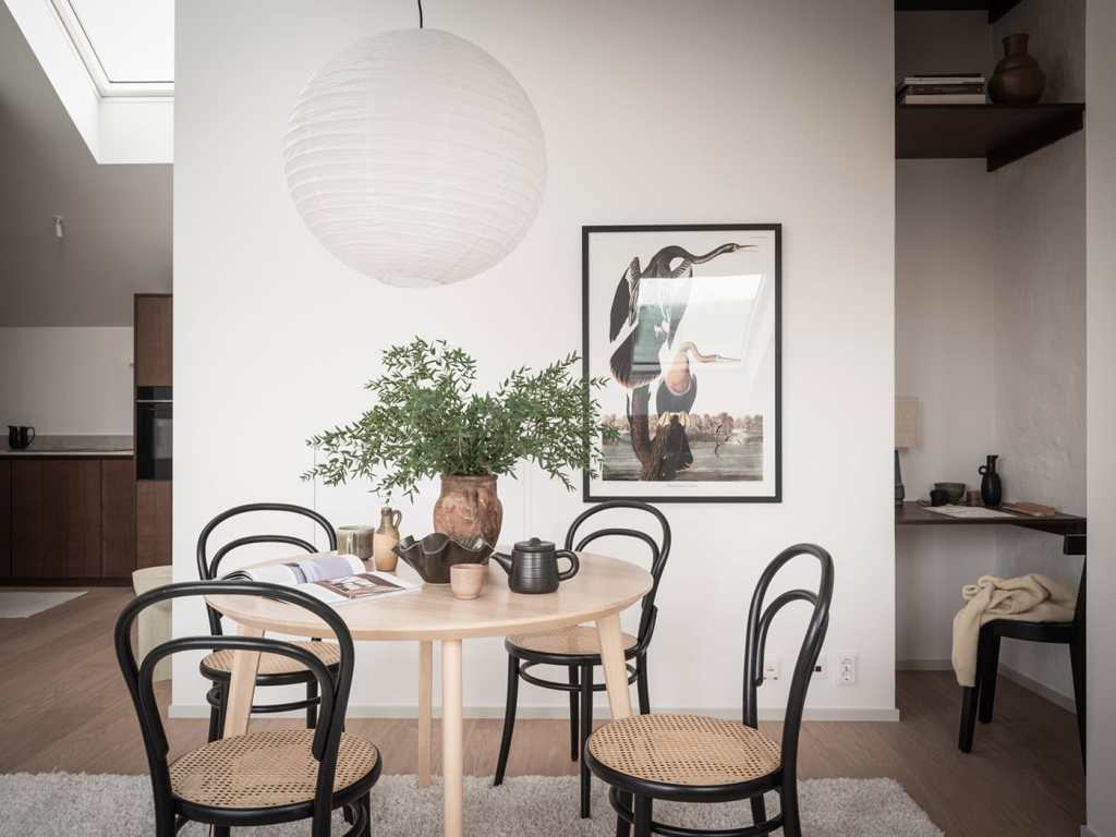 A large living space with a white sofa, off-white area rug, a dining area, and a lounge corner with a daybed