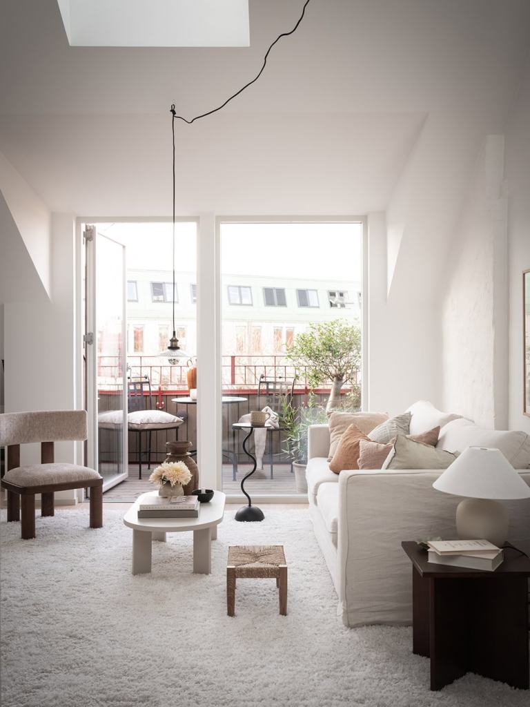 A large living space with a white sofa, off-white area rug, a dining area, and a lounge corner with a daybed