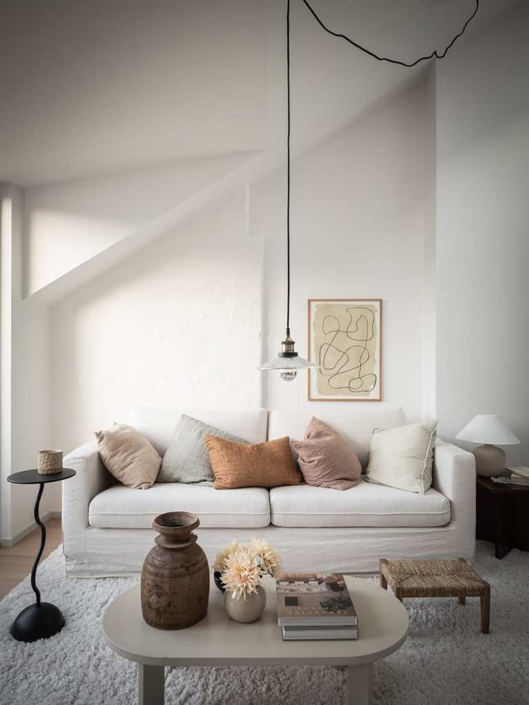 A large living space with a white sofa, off-white area rug, a dining area, and a lounge corner with a daybed