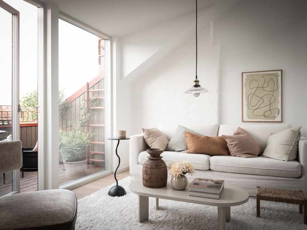 A large living space with a white sofa, off-white area rug, a dining area, and a lounge corner with a daybed