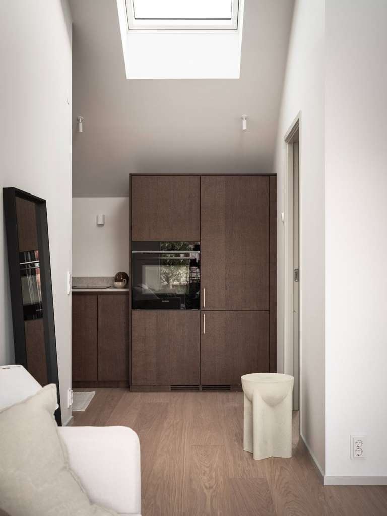 A dark oak kitchen with beige limestone countertops and chrome hardware