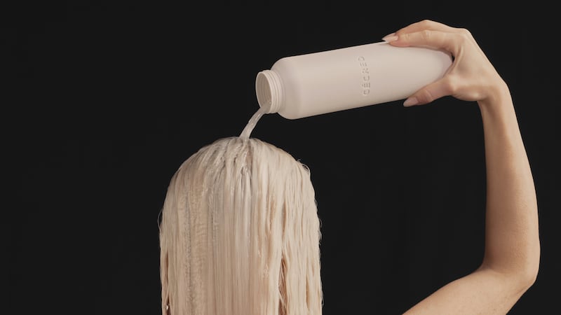 A model pours Cécred's fermented rice water treatment over her hair.