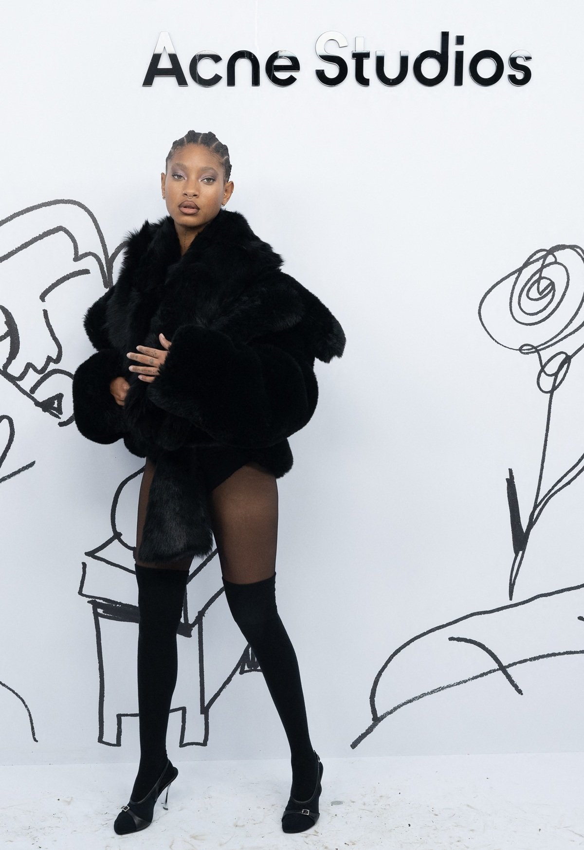 Willow Smith channeled rock-star chic at Acne Studios' Spring/Summer 2025 show, pairing a statement black fur coat and scarf with thigh-high socks, slingback heels, and daring 'naked dressing' pieces for an edgy, runway-inspired look