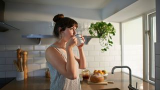 A woman enjoying a drink in her kitchen