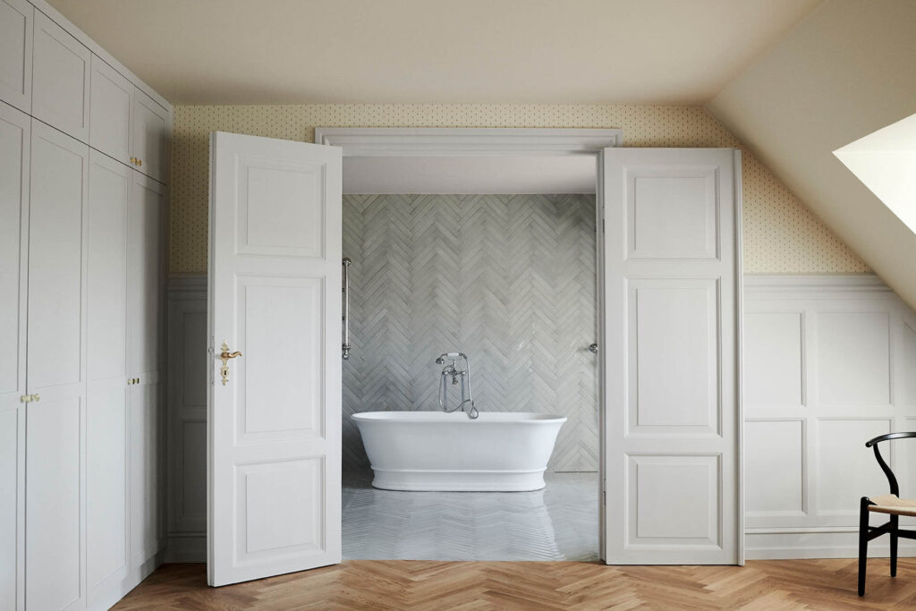 A bathroom with a herringbone pattern wall and floor tile, paired with herringbone hardwood flooring in the bedroom