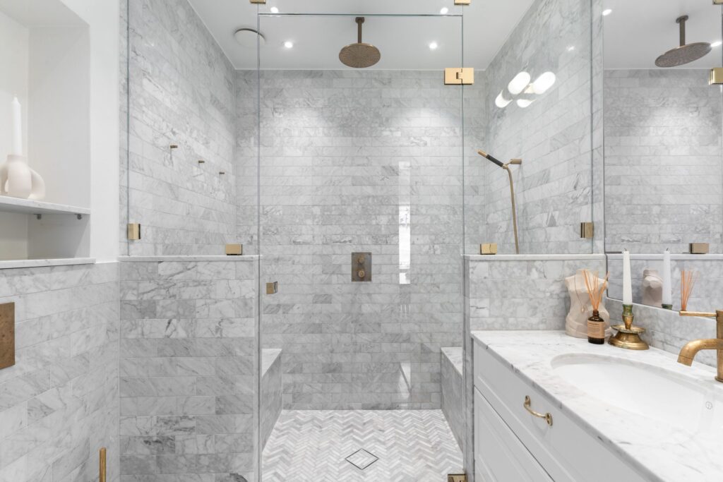 A tiny herringbone pattern on the floor of a shower in a full marble bathroom