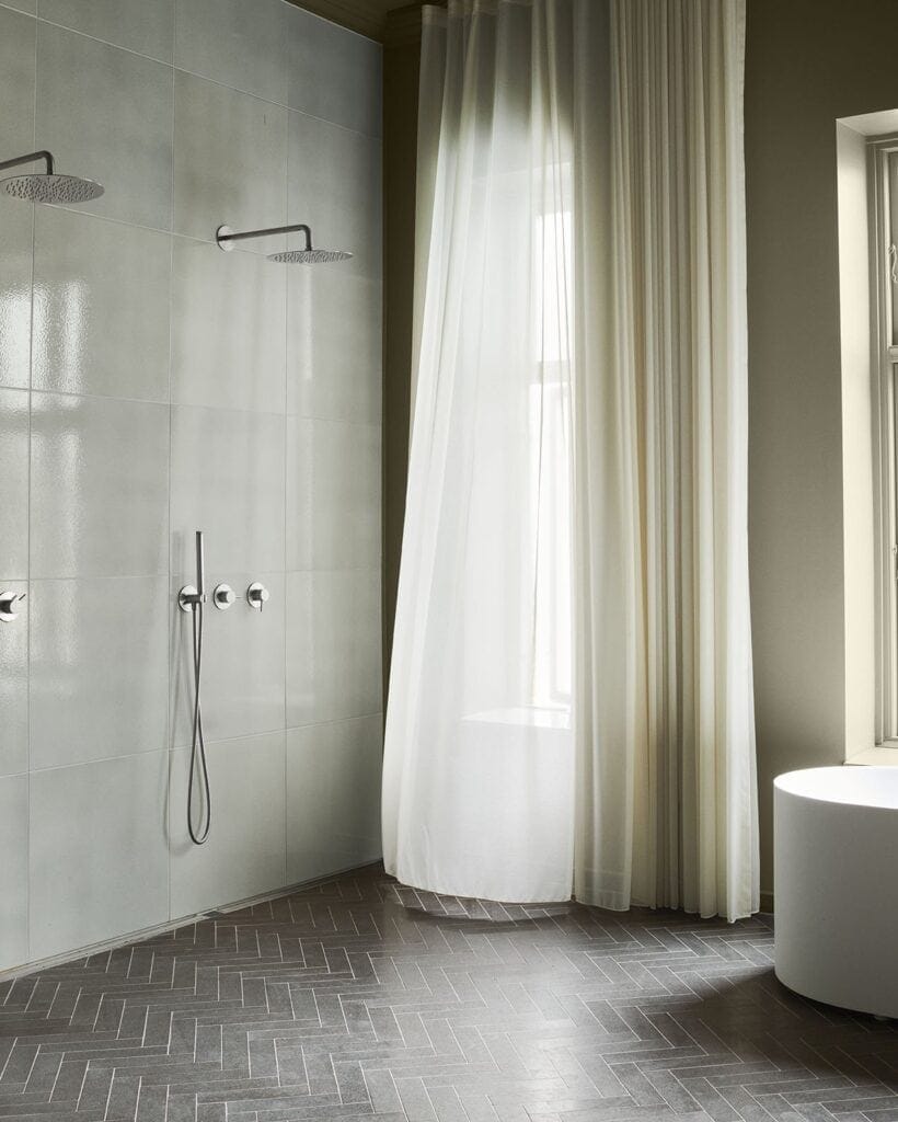 Dark grey herringbone floor tiles paired with stone slab walls in a modern bathroom