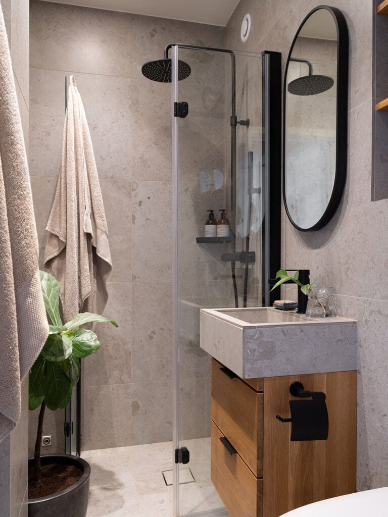 Beige limestone tile paired with a black mirror frame and black fixtures