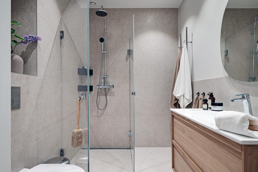 Limestone tiles on the walls and shower of this bathroom, paired with a limestone backsplash behind the sink