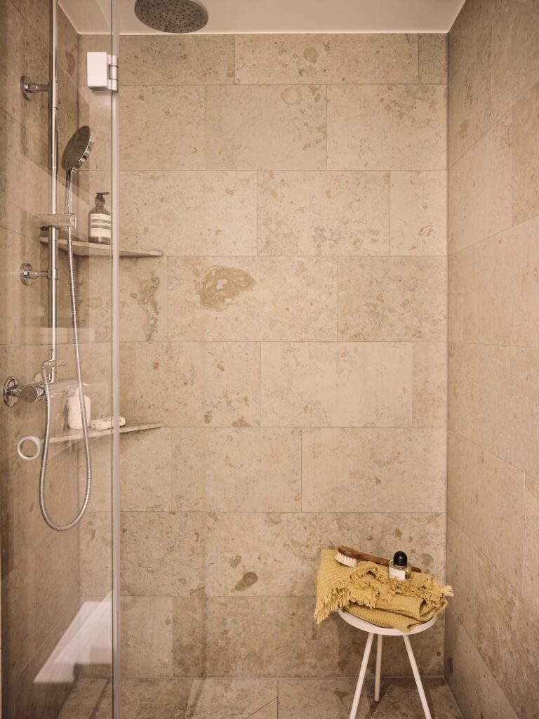 A limestone shower with shower shelves made out of the same material