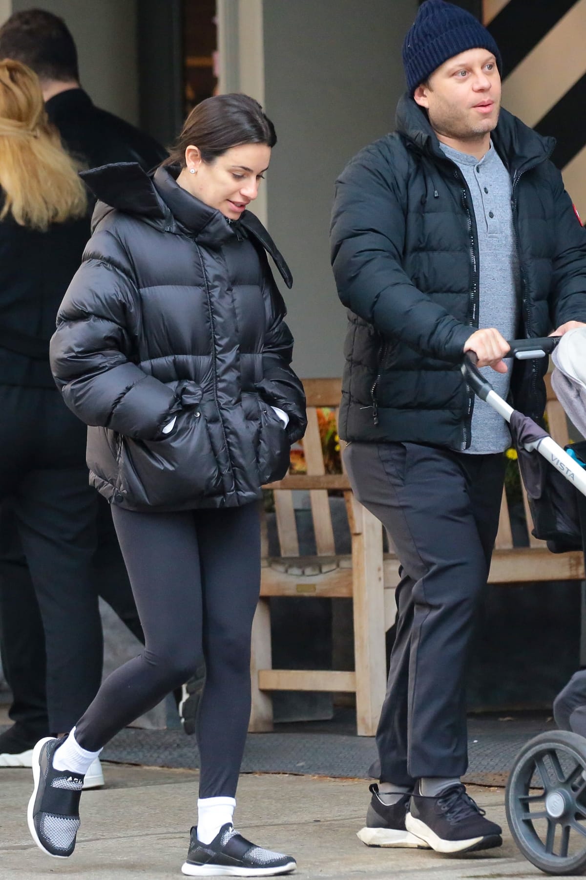 Lea Michele steps out in casual athleisure, wearing black leggings, a puffer jacket, and slip-on sneakers, while on a stroll with Zandy Reich and their child