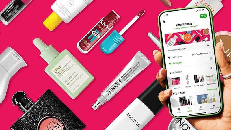 A promotional image for Instacart and Ulta Beauty's partnership. In the foreground, it features a hand holding an iPhone with the Ulta Beauty storefront displayed. Behind the hand, a mosaic of beauty products from Ulta Beauty, including LolaVie conditioner, Black Opium fragrance and Nyx lip gloss, forming a background.