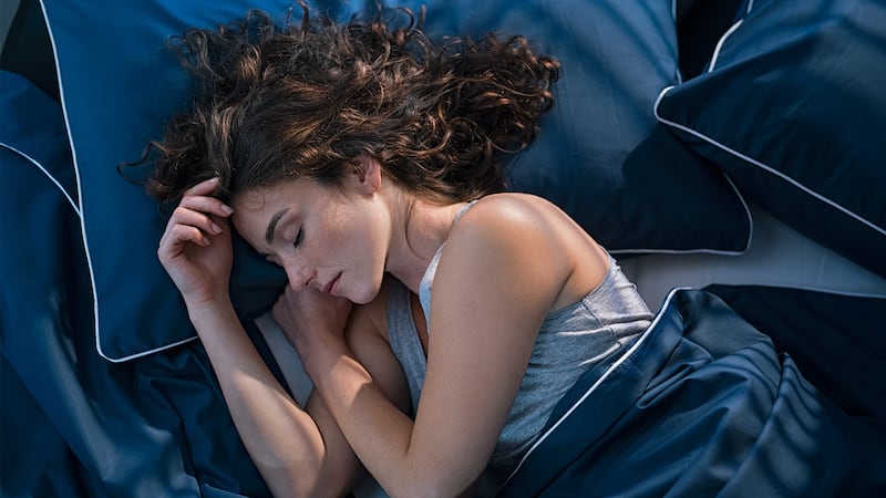 A woman sleeping on a bed with navy sheets