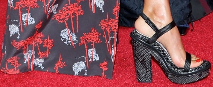 Jessica Alba adds a bold touch to her look with black platform sandals, paired with a striking red and black patterned outfit featuring tiger and bamboo motifs