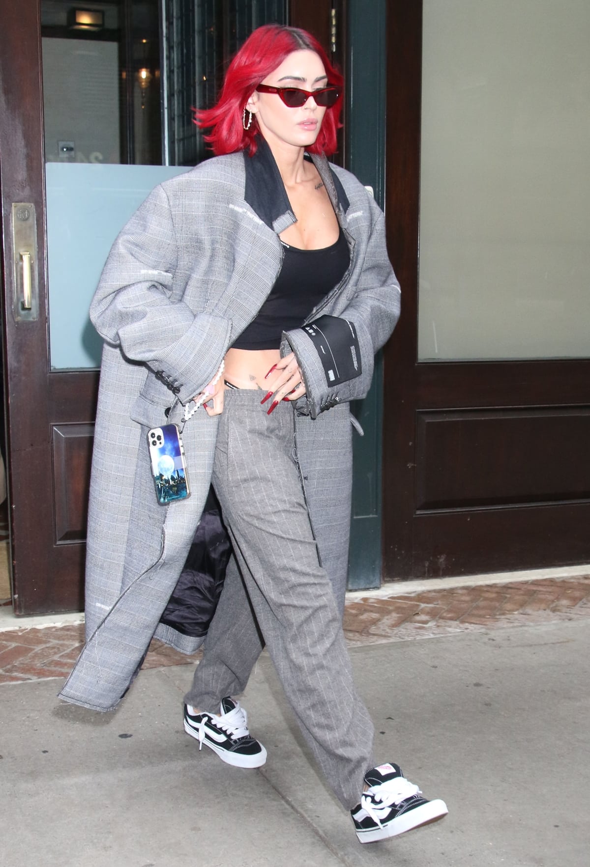 On November 9, 2023, in New York City, Megan Fox was spotted wearing black and white Vans Knu Skool sneakers paired with gray trousers, a black crop top, and an oversized gray coat