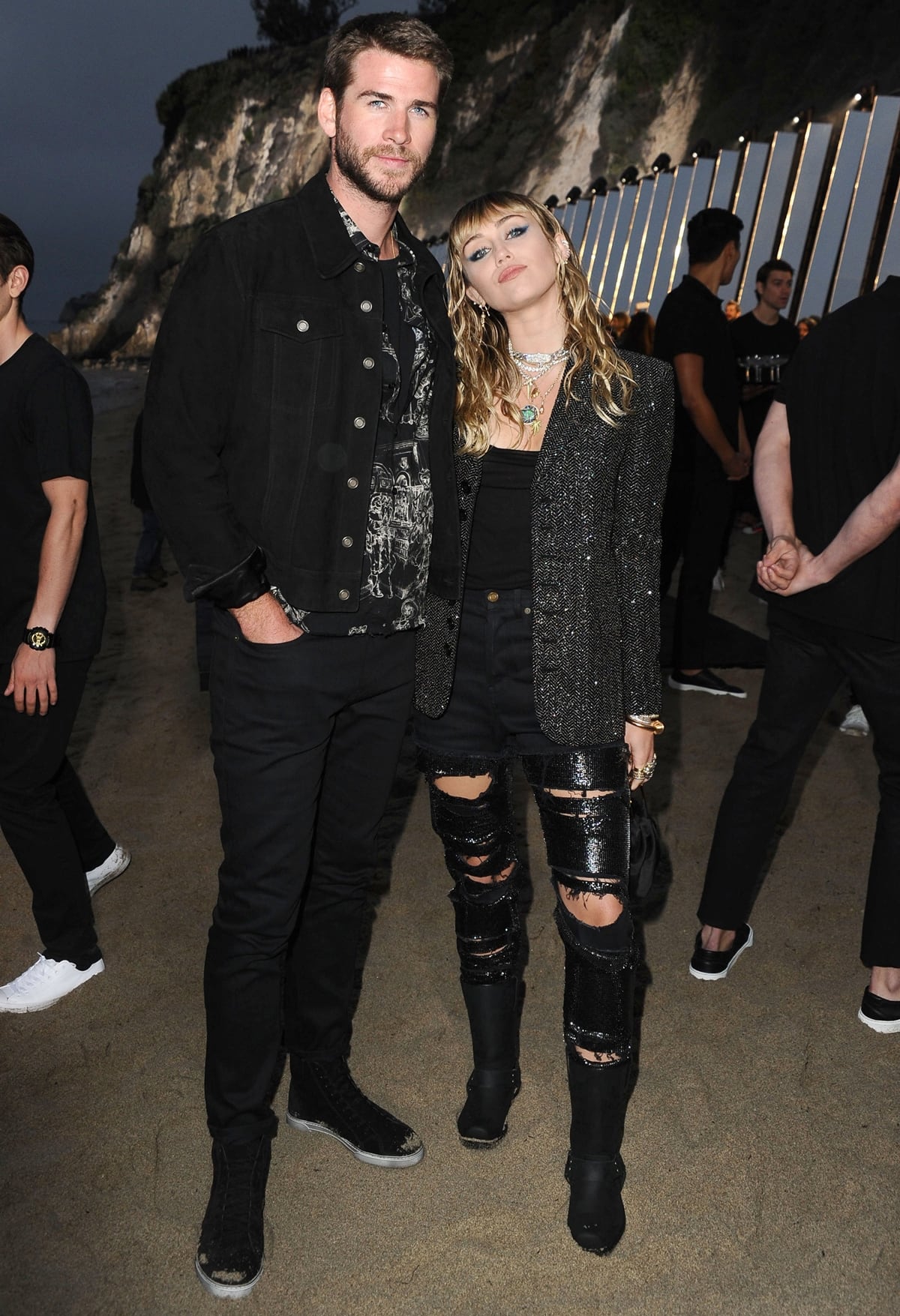 Miley Cyrus rocks a shimmering blazer and ripped sequin pants while posing alongside Liam Hemsworth in casual black denim