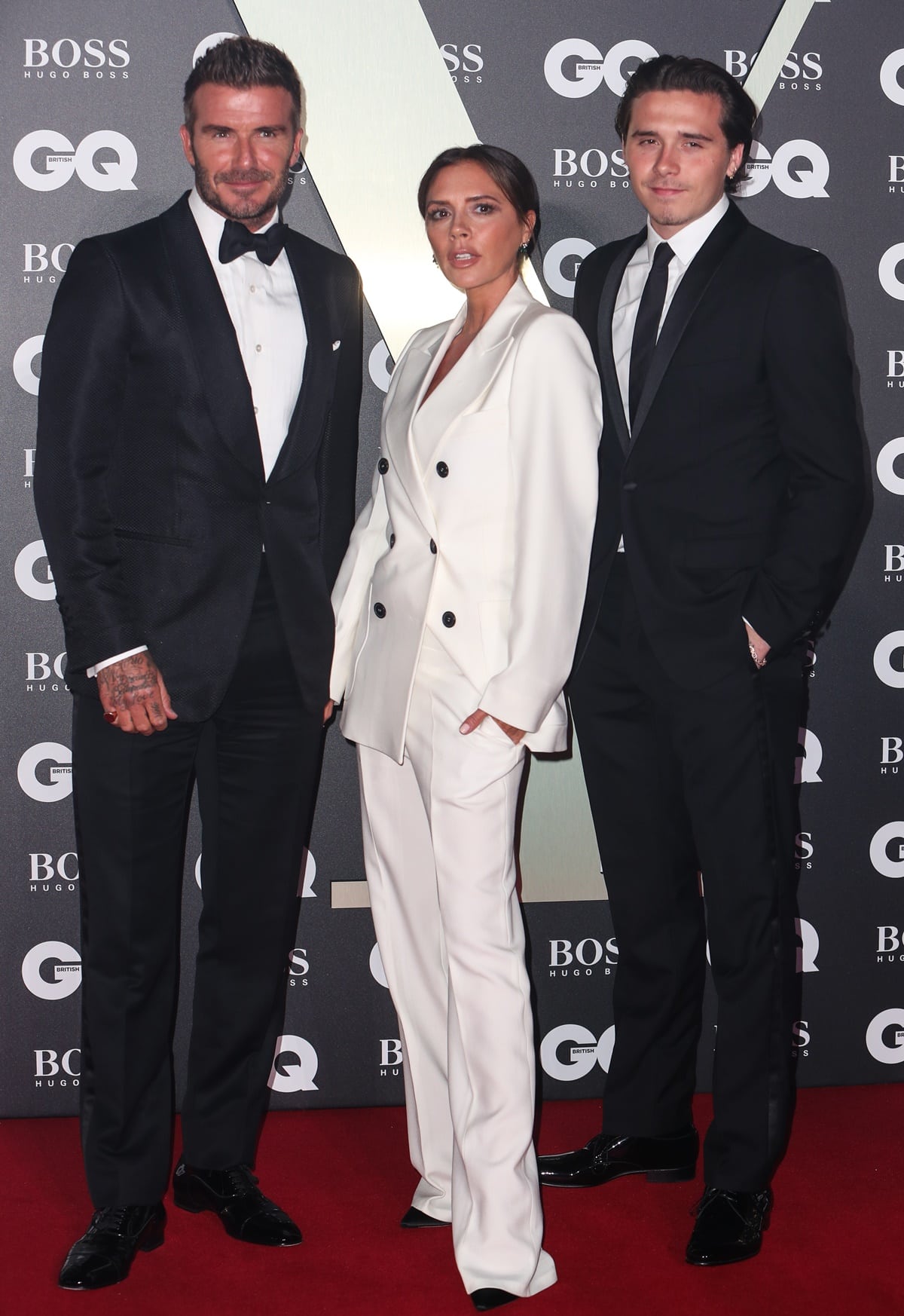 Victoria Beckham stuns in a sleek white tailored suit while posing with David and Brooklyn Beckham at the 2019 GQ Men of the Year Awards